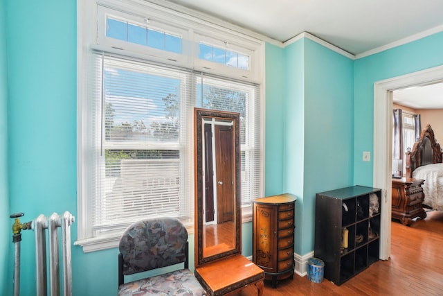 entryway with radiator heating unit, hardwood / wood-style flooring, ornamental molding, and a healthy amount of sunlight