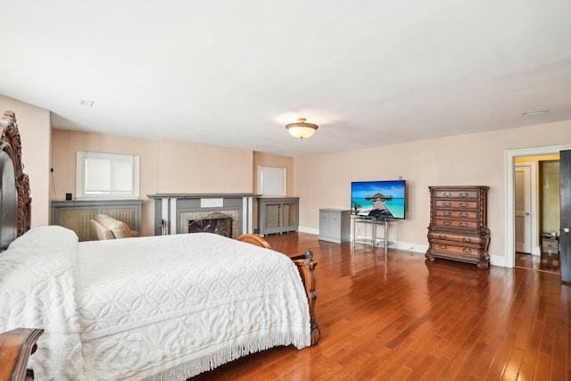 bedroom with hardwood / wood-style floors and a brick fireplace