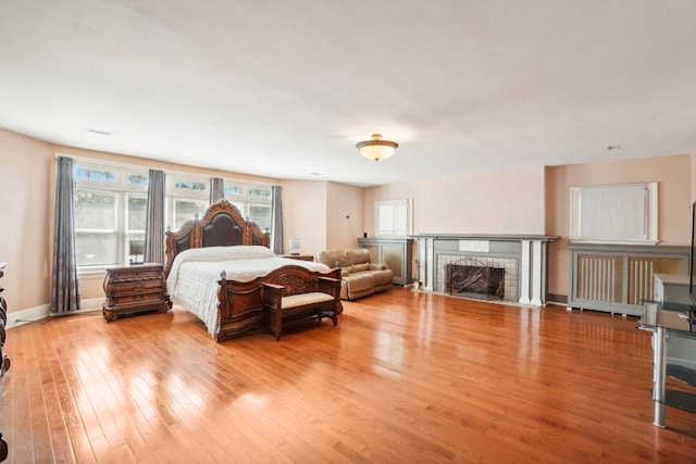 bedroom featuring a tiled fireplace and light hardwood / wood-style flooring