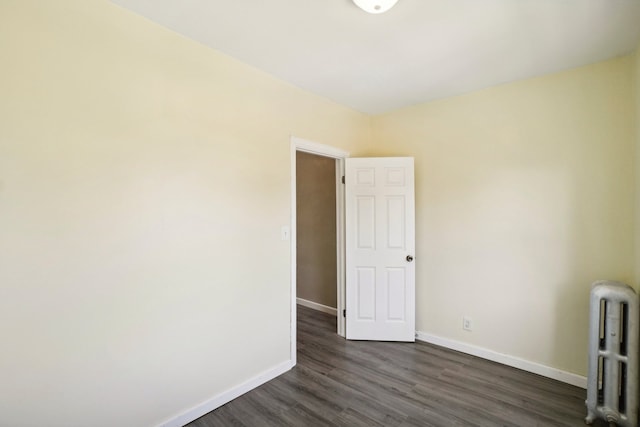 spare room with radiator heating unit and dark hardwood / wood-style floors