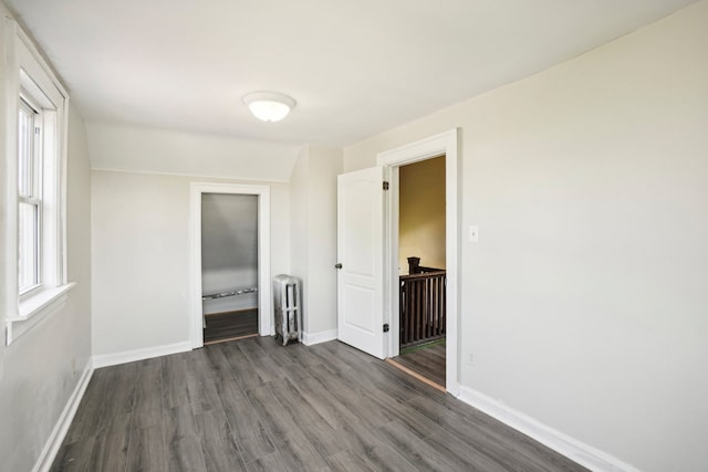 unfurnished bedroom featuring radiator heating unit and dark hardwood / wood-style floors