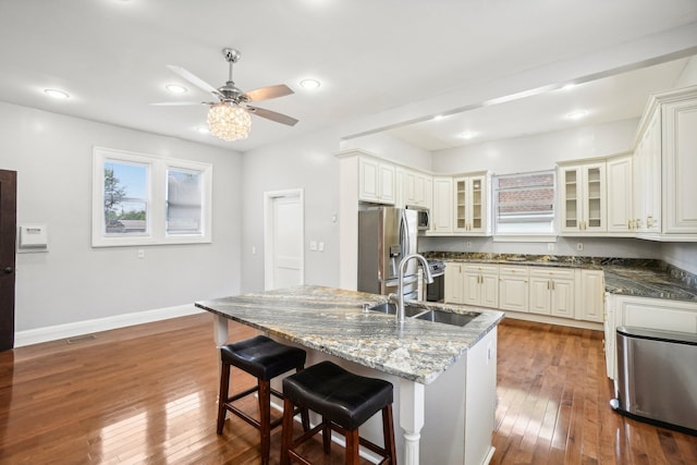 kitchen with sink, wood-type flooring, a kitchen bar, a kitchen island with sink, and appliances with stainless steel finishes