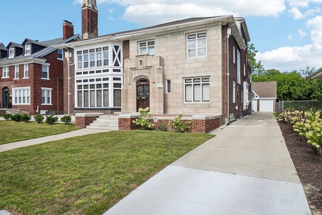 view of front of property featuring a garage, a front lawn, and an outdoor structure