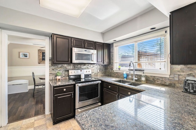 kitchen with sink, tasteful backsplash, light hardwood / wood-style flooring, dark brown cabinets, and appliances with stainless steel finishes