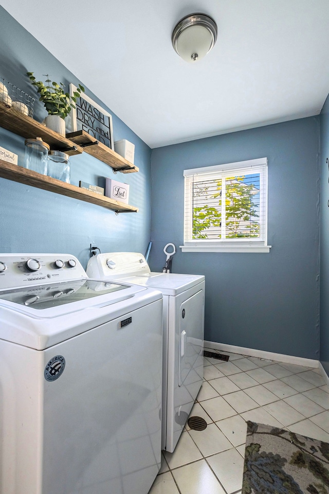 clothes washing area with light tile patterned floors and washer and clothes dryer