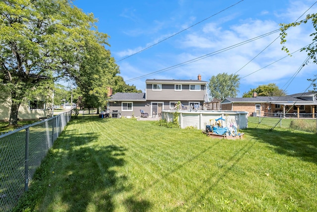 rear view of house with a fenced in pool and a yard