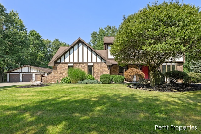 tudor-style house with a garage, a front lawn, and an outdoor structure