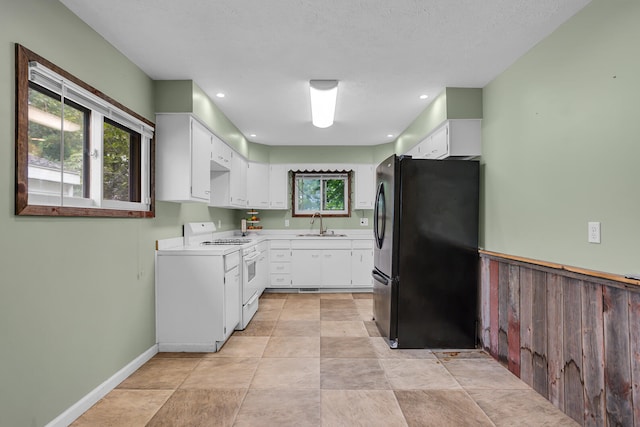 kitchen featuring black fridge, a textured ceiling, sink, electric range, and white cabinetry