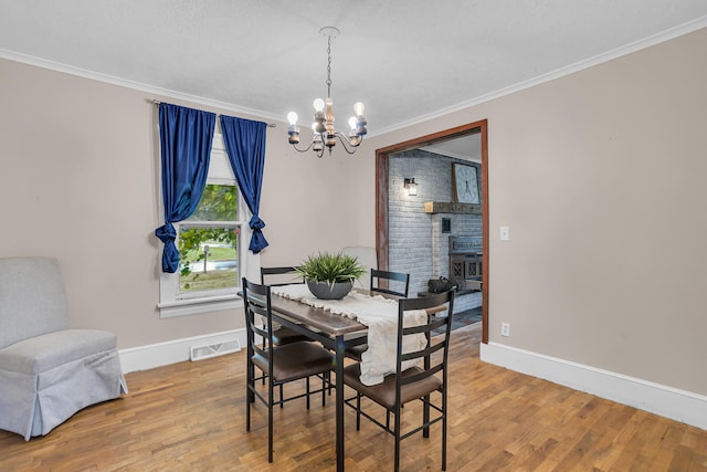 dining area with a chandelier, wood-type flooring, and crown molding