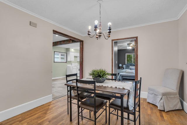 dining space with washer and dryer, wood-type flooring, an inviting chandelier, and ornamental molding