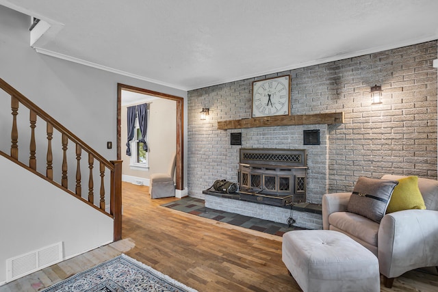 living room featuring a wood stove, hardwood / wood-style floors, and brick wall