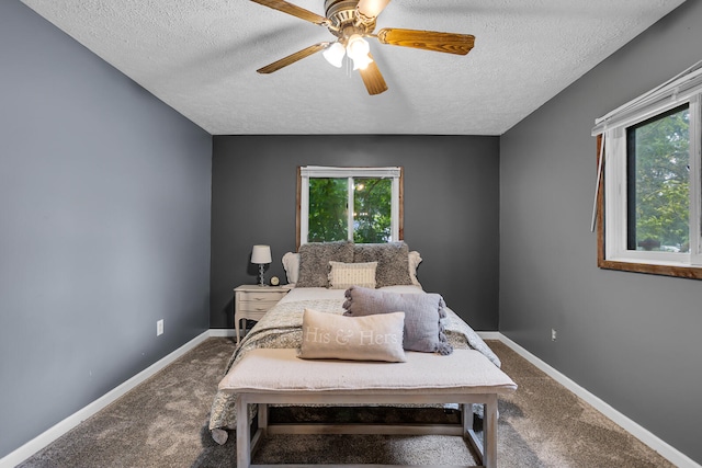 carpeted bedroom featuring multiple windows, a textured ceiling, and ceiling fan