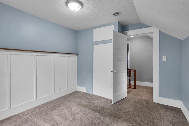 interior space featuring a closet, carpet floors, a textured ceiling, and vaulted ceiling