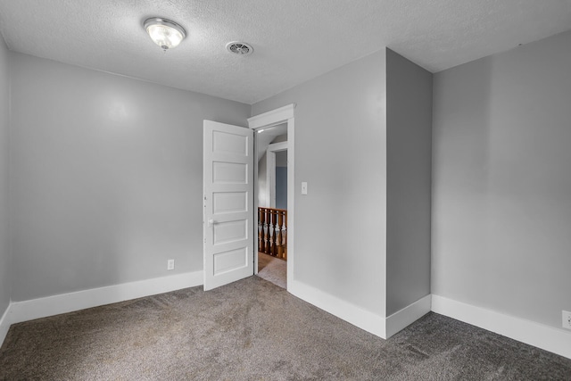 spare room with a textured ceiling and dark carpet