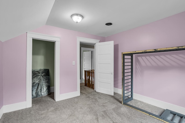 unfurnished bedroom with light colored carpet and vaulted ceiling