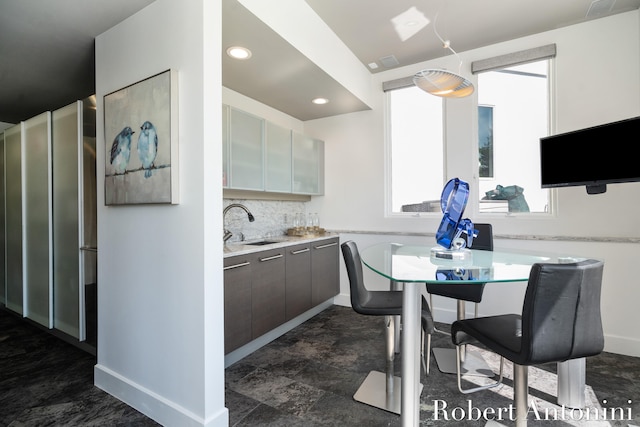 kitchen featuring tasteful backsplash, dark brown cabinetry, and sink