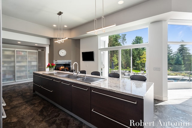 kitchen with a wealth of natural light, a center island with sink, pendant lighting, and sink