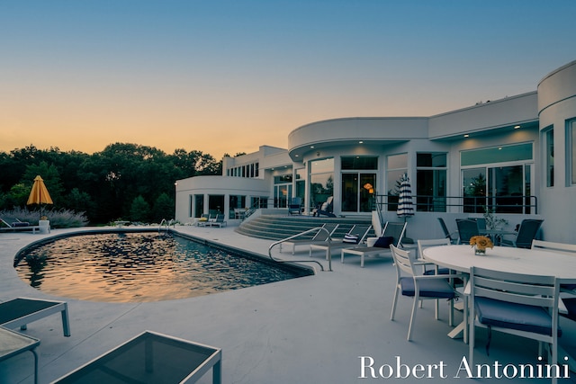 pool at dusk with a patio area