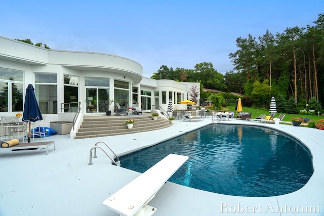 view of pool with a diving board and a patio