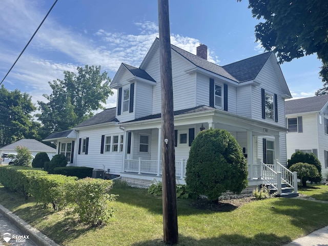 view of front of property featuring cooling unit, a front yard, and covered porch