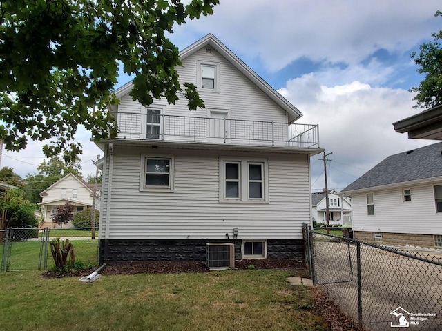 back of house with a balcony, a yard, and central AC