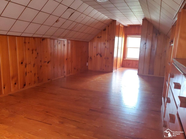 bonus room with hardwood / wood-style flooring, vaulted ceiling, and wood walls