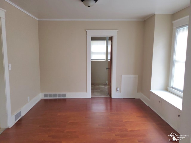 unfurnished room featuring plenty of natural light, dark hardwood / wood-style floors, and ornamental molding