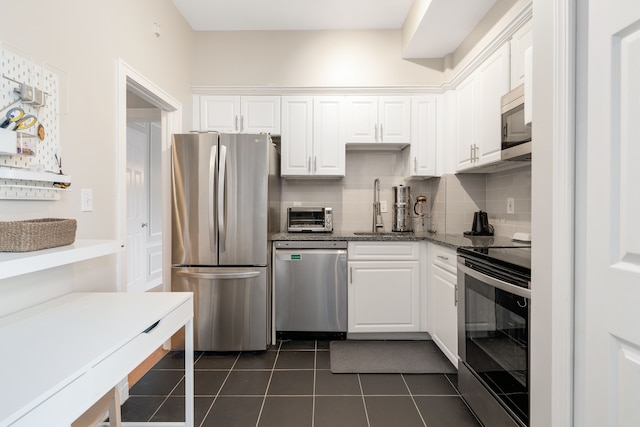 kitchen with sink, decorative backsplash, dark tile patterned floors, white cabinetry, and stainless steel appliances