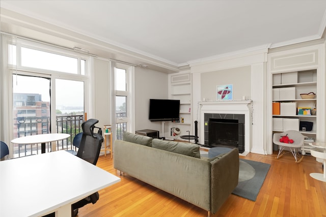 living room featuring a tiled fireplace, crown molding, and light hardwood / wood-style floors