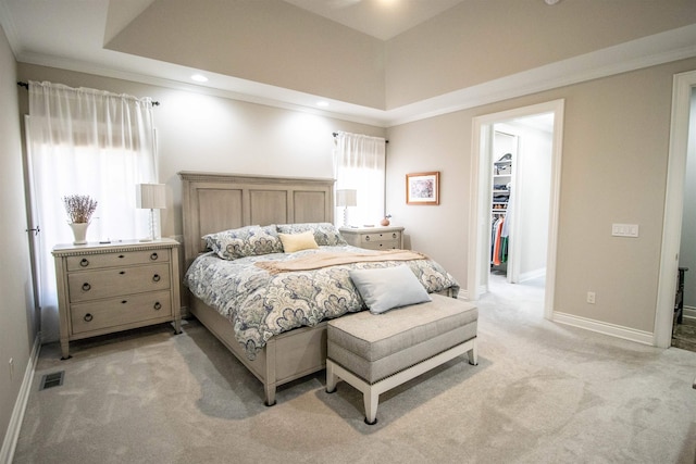 bedroom featuring light colored carpet, a spacious closet, and multiple windows