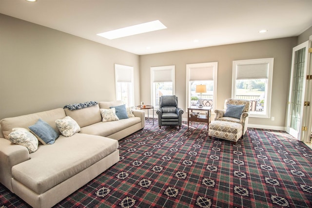 living room with carpet floors, a wealth of natural light, and a skylight