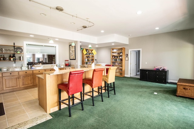 kitchen featuring a center island with sink, a kitchen breakfast bar, light stone counters, and light carpet