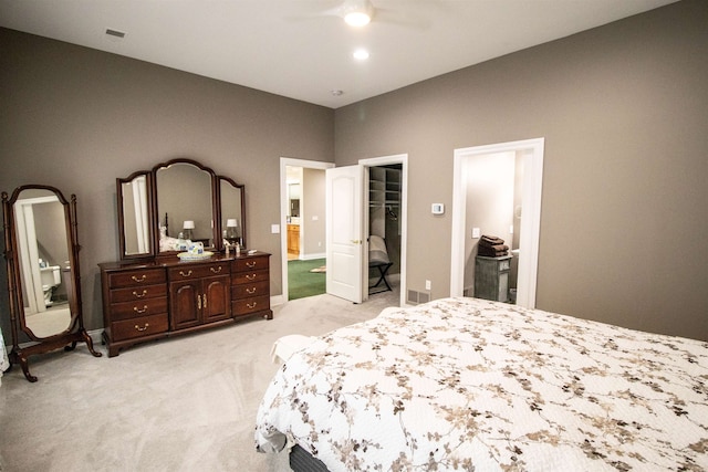 bedroom with light carpet, a walk in closet, a closet, and ceiling fan