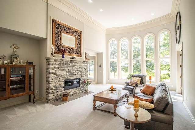 carpeted living room with a high ceiling, a stone fireplace, and ornamental molding