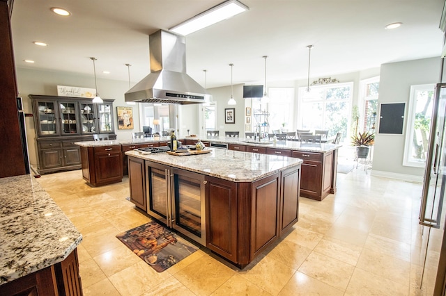 kitchen featuring island exhaust hood, pendant lighting, kitchen peninsula, and a kitchen island