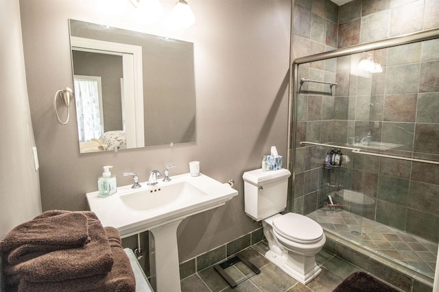 bathroom featuring tile patterned flooring, toilet, and an enclosed shower