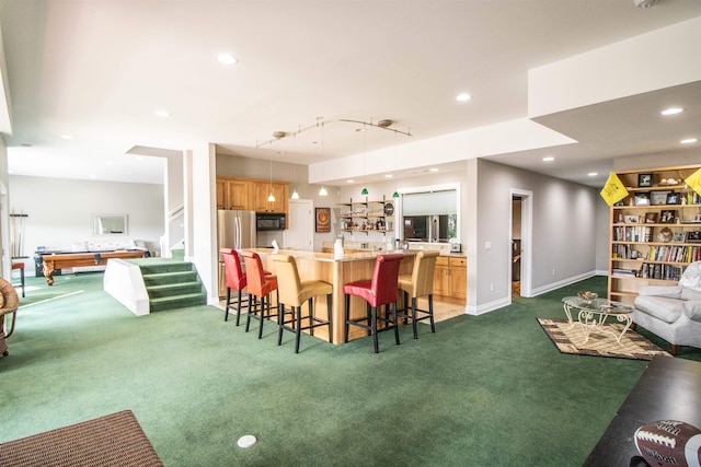 kitchen with a breakfast bar, a center island, pendant lighting, and dark carpet