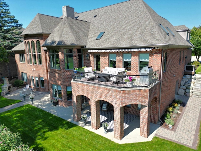 rear view of property featuring an outdoor hangout area, a balcony, a patio area, and a lawn