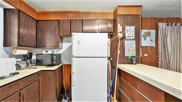 kitchen with white fridge and wood walls
