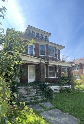 italianate house with a porch, a balcony, and a front lawn