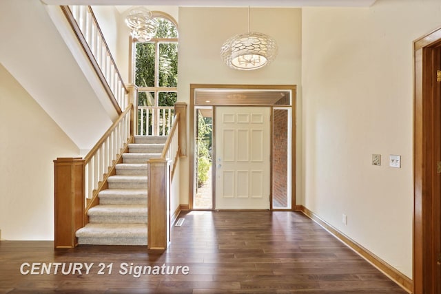 foyer entrance with a healthy amount of sunlight, dark hardwood / wood-style flooring, and a chandelier