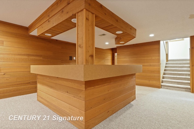 interior space featuring wooden walls, beamed ceiling, and light colored carpet