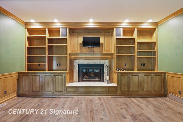 unfurnished living room with a tiled fireplace, crown molding, and light hardwood / wood-style floors