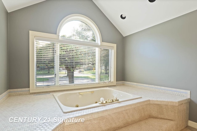 bathroom with tiled bath and lofted ceiling