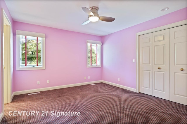 unfurnished bedroom with multiple windows, ceiling fan, and dark colored carpet