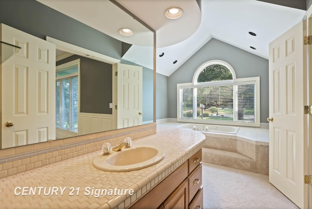 bathroom with vanity, a relaxing tiled tub, and lofted ceiling