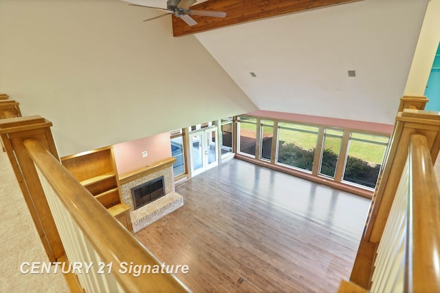 living room featuring hardwood / wood-style floors, high vaulted ceiling, a brick fireplace, ceiling fan, and beamed ceiling