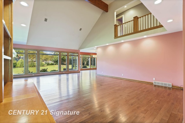 unfurnished living room with wood-type flooring, high vaulted ceiling, and beam ceiling