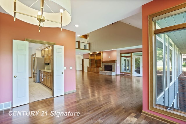 unfurnished living room with a fireplace, light hardwood / wood-style flooring, and high vaulted ceiling