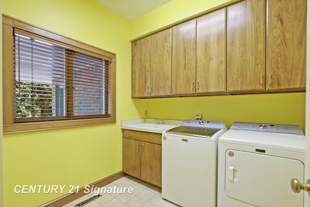 clothes washing area with washing machine and clothes dryer, sink, light tile patterned flooring, and cabinets